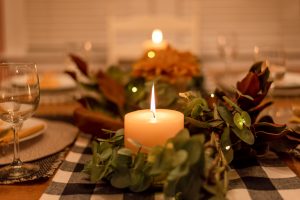 Candles with flowers and plants made into a farmhouse dining room centerpiece in a rustic home.