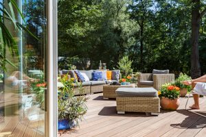 A rustic home's backyard in summer, showing colorful furniture, fixtures, and greeneries