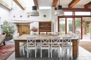 Traditional Spanish farmhouse dining room decorated with wooden furniture and fixtures, and big windows.