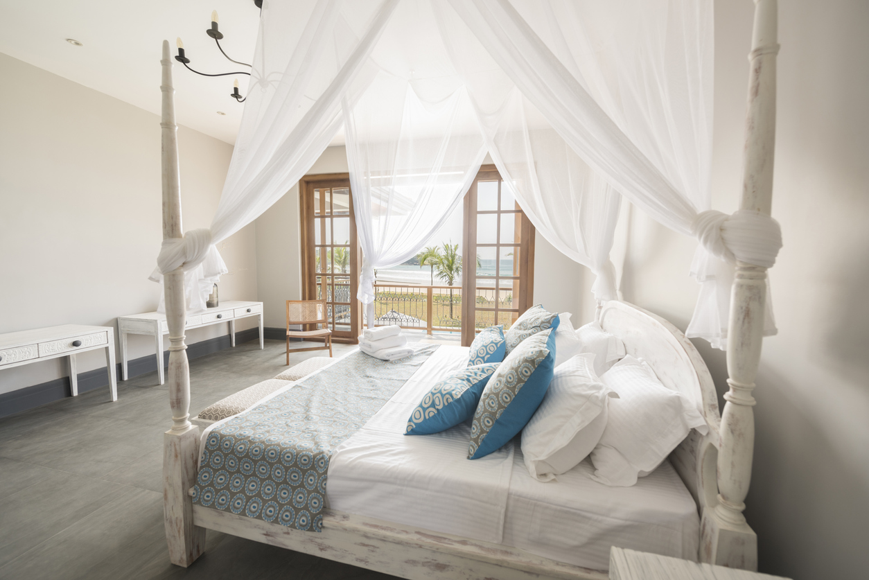Rustic farmhouse bedroom featuring a four-poster bed and white furniture and fixtures.
